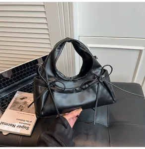 Detailed view of black faux leather tote bag with ribbon bows and pleated handles