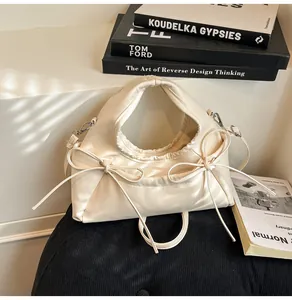 Detail view of cream bow tote bag with soft leather texture and elegant metal buckles