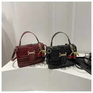 Détail du sac en cuir verni façon crocodile avec breloque cerise et boucle en H