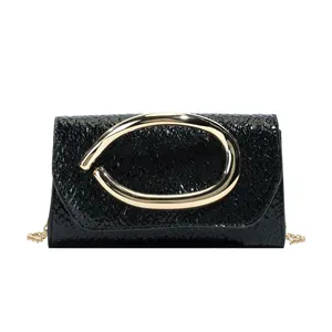 Minimalist black embossed patent leather square bag with large gold buckle and chain