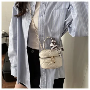 Close-up of beige quilted mini crossbody bag with silk scarf handle and gold hardware