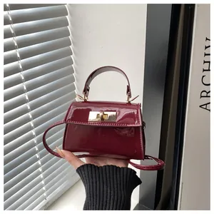 Macro shot of glossy burgundy patent leather bag with gold rotating lock detail