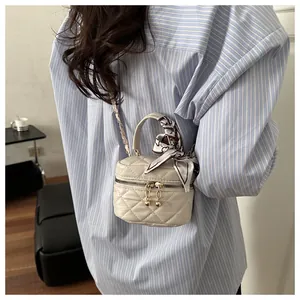 Chic mini quilted crossbody bag with gold chain and silk scarf detail on a model