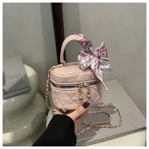 Detail of pink quilted mini bag with gold ball zipper and scarf-wrapped handle