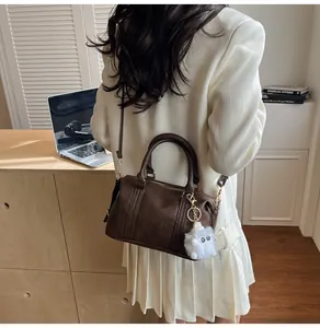Detailed view of dark brown retro barrel bag with plush doll charm and adjustable strap