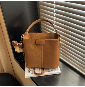 Close-up of brown bucket bag with plush bear charm on minimalist interior windowsill