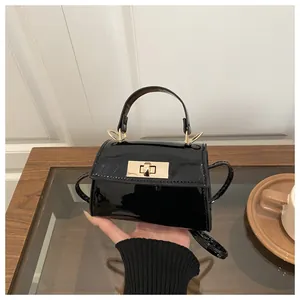 Close-up of black patent leather handbag with a gold metal twist lock and top handle