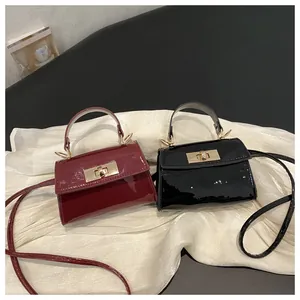 Detailed shot of burgundy and black patent leather mini bags on a white textured background