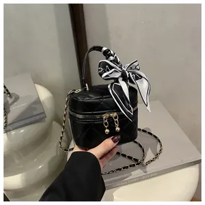 Detail of mini black quilted bag with gold chain strap and decorative floral silk scarf
