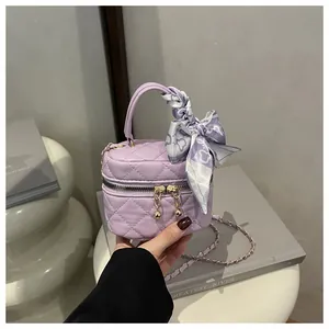 Detail of light purple quilted mini bag with golden chain and floral silk scarf handle