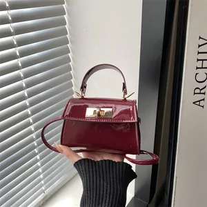Elegant wine red patent leather mini handbag with gold rotating clasp and shoulder strap