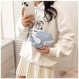 Light blue mini square bag with plush white wings held by a model in a casual outfit