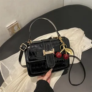 Sac à main chic en cuir verni croco noir avec pendentif cerise et finitions dorées