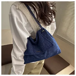 Detail of blue denim shoulder bag featuring a metal chain strap and flap closure