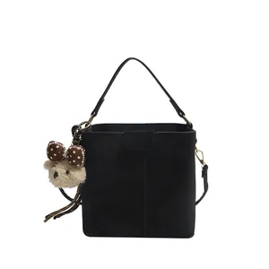 Black bucket shoulder bag in suede leather featuring a cute plush bear pendant