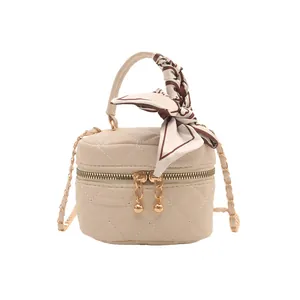 Beige quilted mini crossbody bag with gold hardware, decorative scarf and chain strap