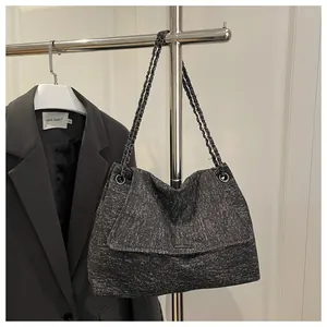 Close-up of the tweed chain bag texture showing grey woven fabric and metallic bar detail