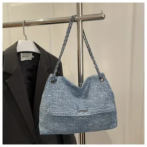 Close-up of blue denim texture tote bag with silver metal chain strap and flip cover