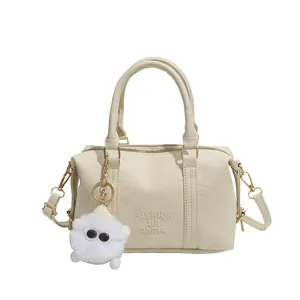 Cream white Boston bag with litchi texture leather and plush charm on white background