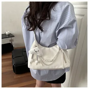 Details einer weißen Nylon-Schultertasche mit Silberketten, Perlen und Wolkenanhänger