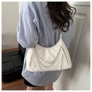 Detailansicht der weißen Hobo-Tasche mit Perlenkette und langen Quasten auf der Schulter