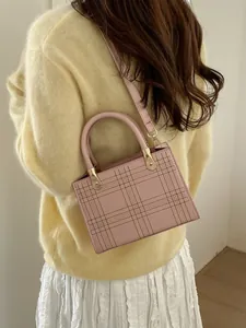 Pink minimalist tote bag with quilted grid pattern shown on model in soft lighting