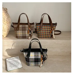 Detailed view of woven plaid mini bucket bags with leather handles and beaded tassels