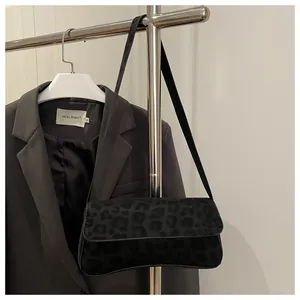 Detailed view of black leopard print underarm bag with velvet texture on a hanger