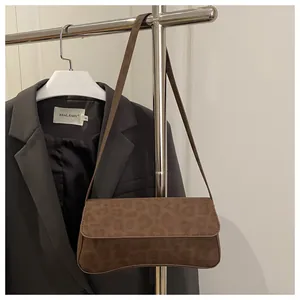 Detail of vintage leopard print shoulder bag in brown suede texture on a metal hanger
