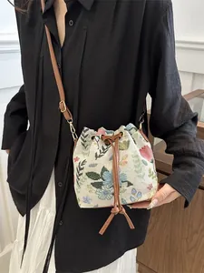 Ethnic style embroidered floral bucket bag with brown drawstring and gold hardware details