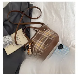 Detail of checkered plaid tote bag with wooden bead tassel and adjustable strap