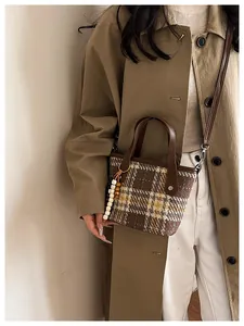 Detail of plaid tweed tote bag with leather handles and colorful beaded charm accessory