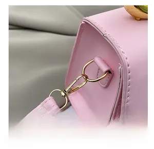 Detailed close-up of a pink leather handbag featuring a polished gold metal shoulder strap hook