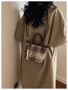 Detail of vintage plaid tote bag with wooden beads and leather strap on camel coat