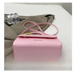 Detail view of pink leather crossbody bag with flap closure and gold lettering