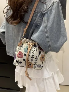 Ethnic style floral drawstring bucket bag with leather strap shown on a model