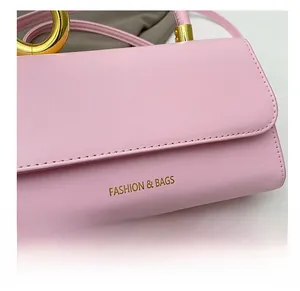 Detailed close-up of pink leather crossbody bag with golden fashion letter logo and stitching