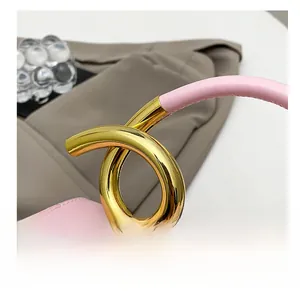 Detail of pink leather handbag showing golden metal ring handle and premium stitching