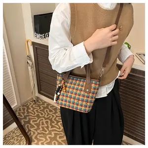 Detail of colorful houndstooth tote bag with beaded charm and brown leather straps