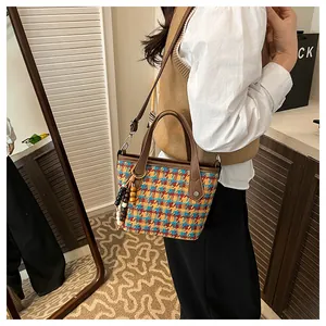 Detail of colorful houndstooth tote bag with brown leather handles and bead tassel