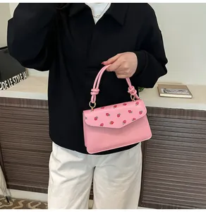 Détail du sac à main rose avec imprimés fraises et finitions métalliques dorées