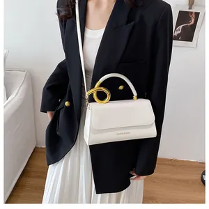 Detail view of white leather shoulder bag with golden ring hardware on black blazer