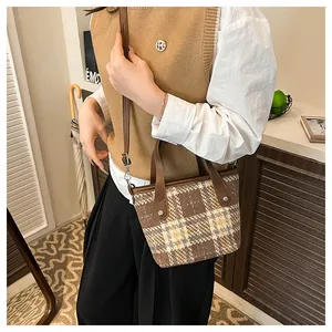 Detail of checkered tote bag with brown leather handles and silver rivet accents