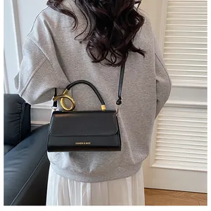 Detail of black leather flap handbag featuring gold twisted metal rings on the handle