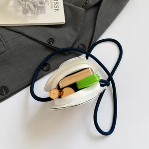 Detalle de la capacidad interior del mini bolso blanco con correa de cuerda azul