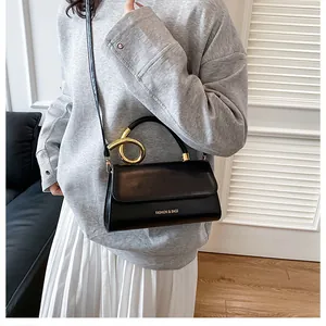 Detail of elegant black faux leather bag with unique twisted gold metal handle and strap