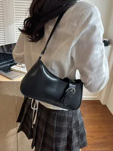 Minimalist black faux leather shoulder bag for women with silver buckle detail in lifestyle setting