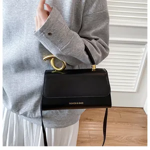 Close-up of a black leather bag featuring a unique gold twisted metal handle and lettering