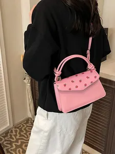 Sac à main rose avec imprimé fraise et poignées, vue arrière portée par un modèle