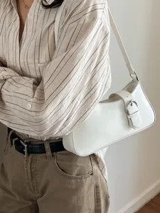Minimalist white baguette shoulder bag with large silver ring buckle on a female model